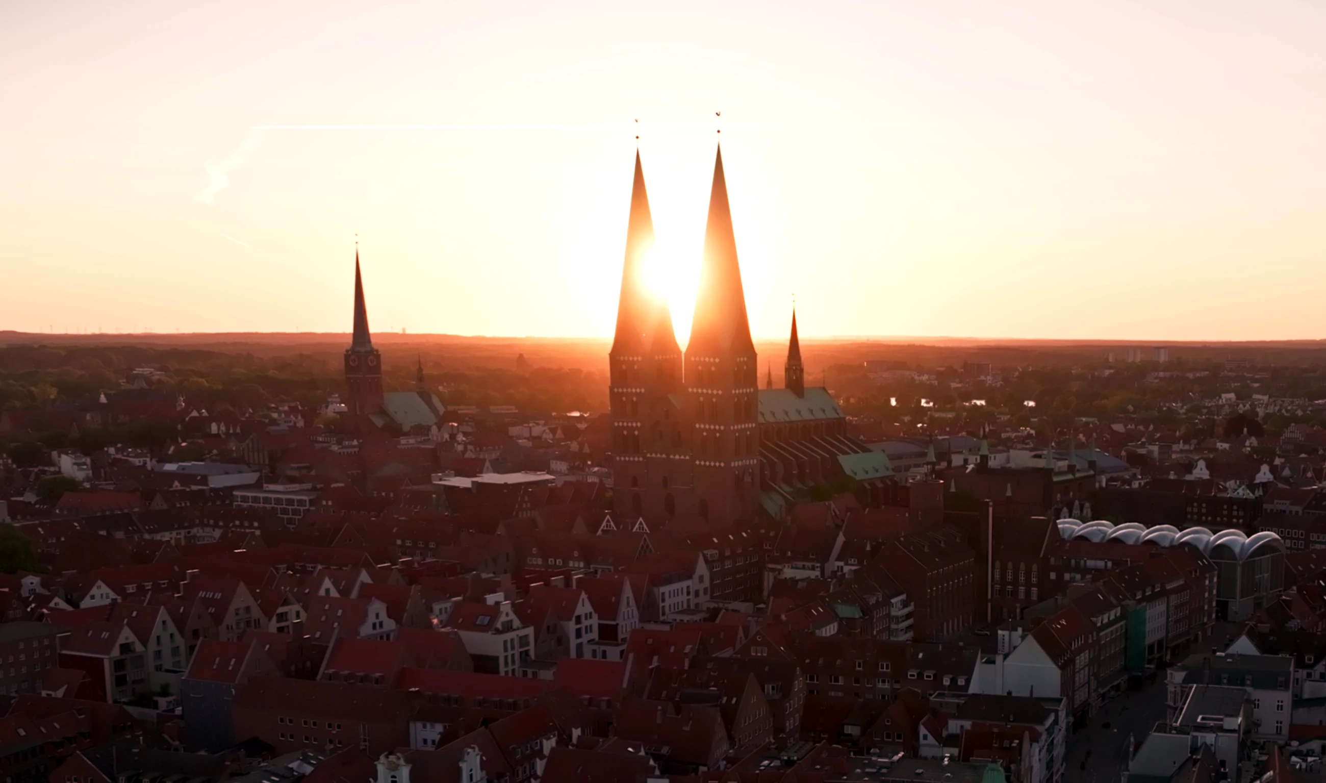 Aufgehende Sonne zwischen den beiden Türmen von St. Marien vom Holstentor aus gesehen